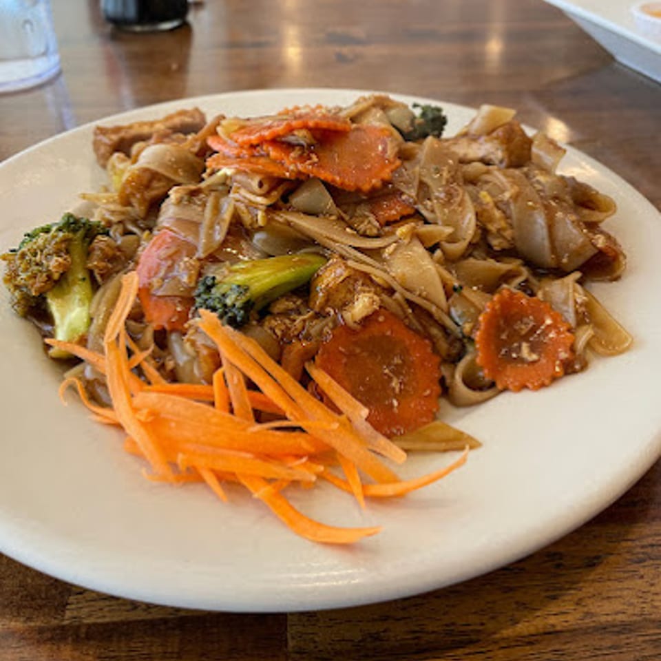 A plate of Thai Chili Asian Bistro's Pad See Ew with wide noodles, broccoli, and carrots.
